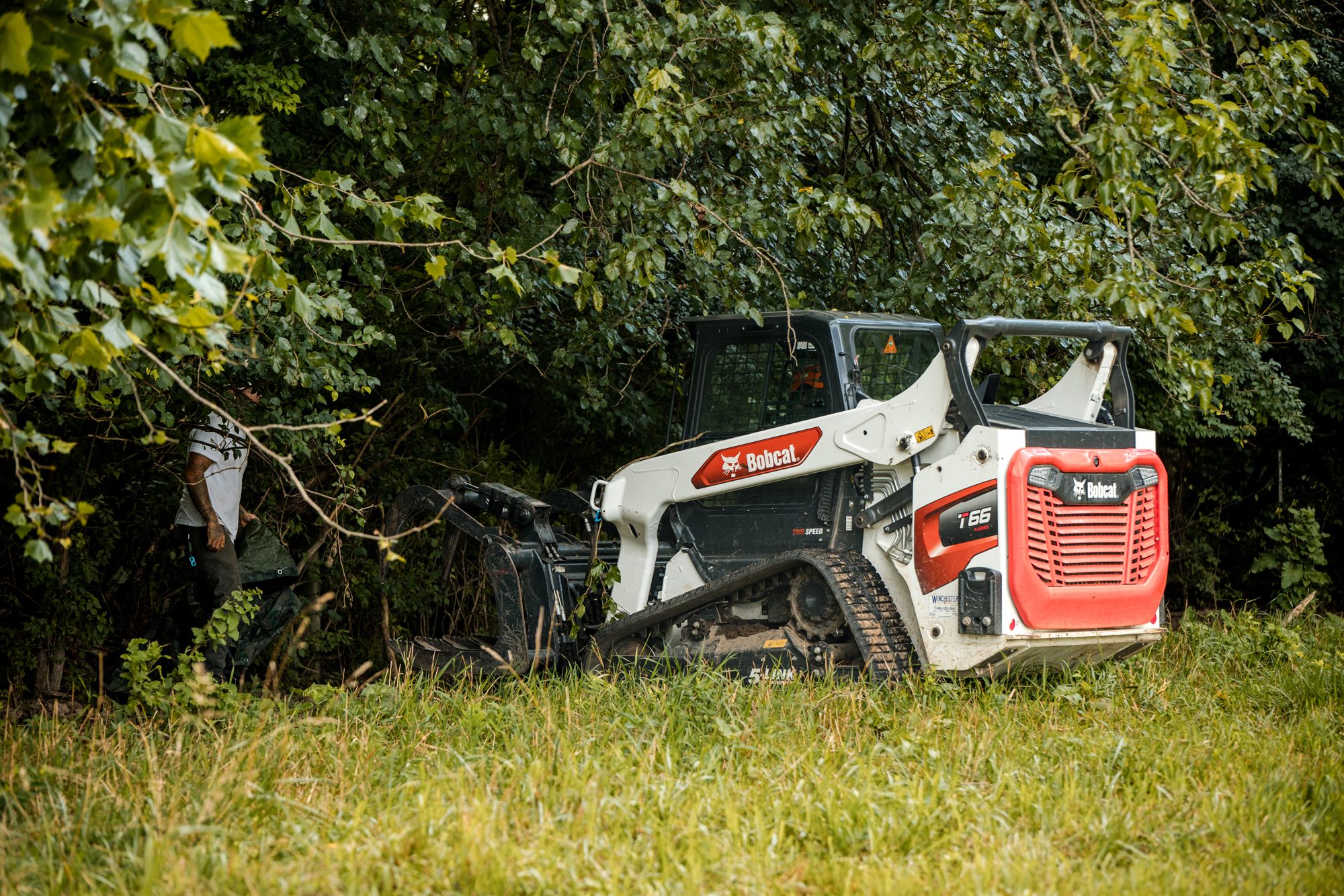 Bobcat skid steer working at the tree line on a Berryville, VA job site
