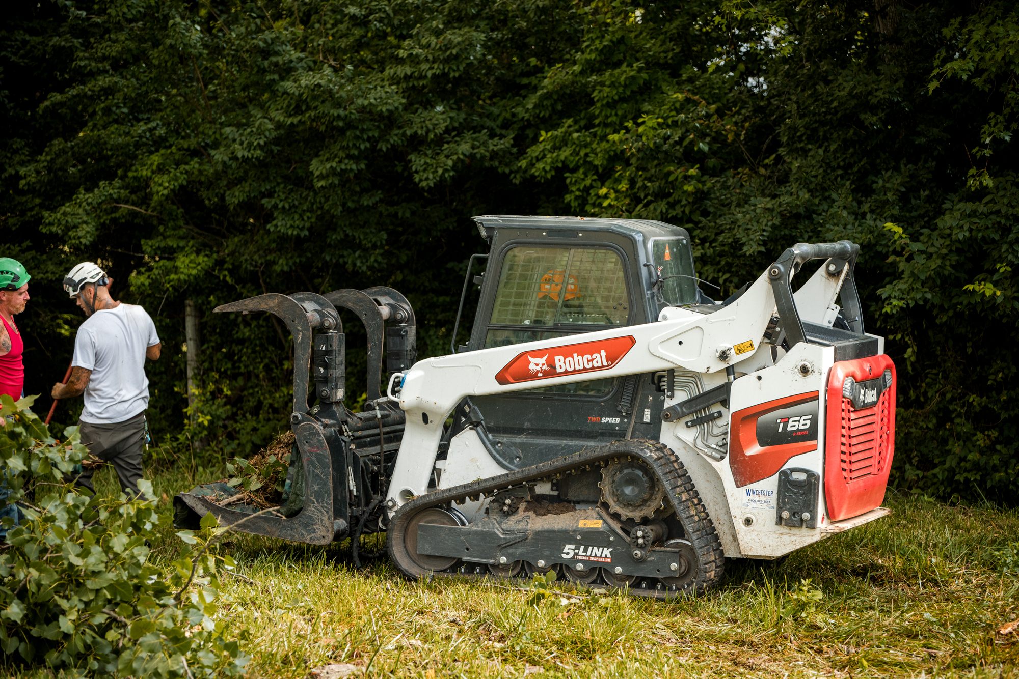 Bobcat skid steer hauling a load of cut brush across an open pasture near Berryville, VA