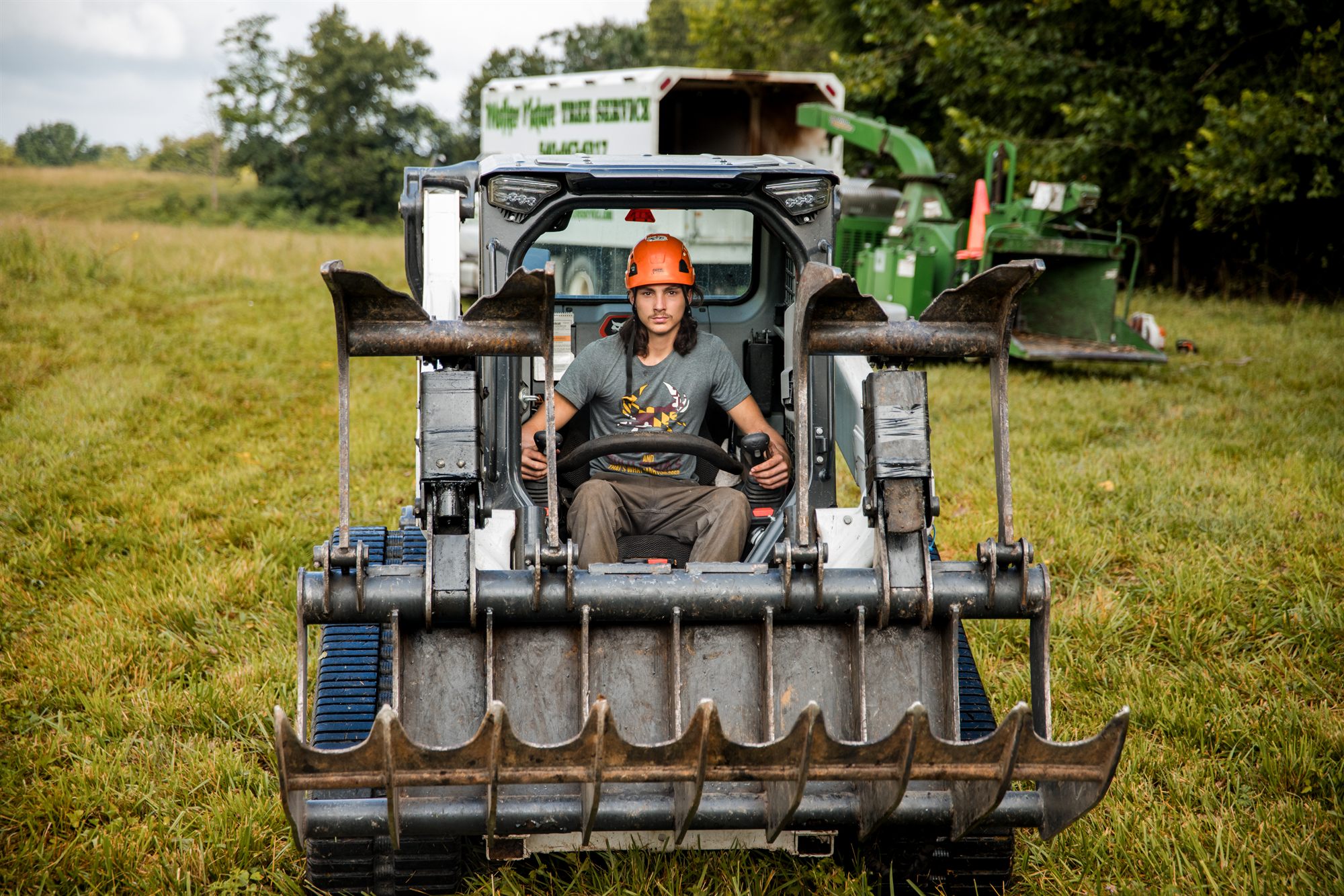 Crew member operating a skid steer on a tree job near Winchester, Virginia