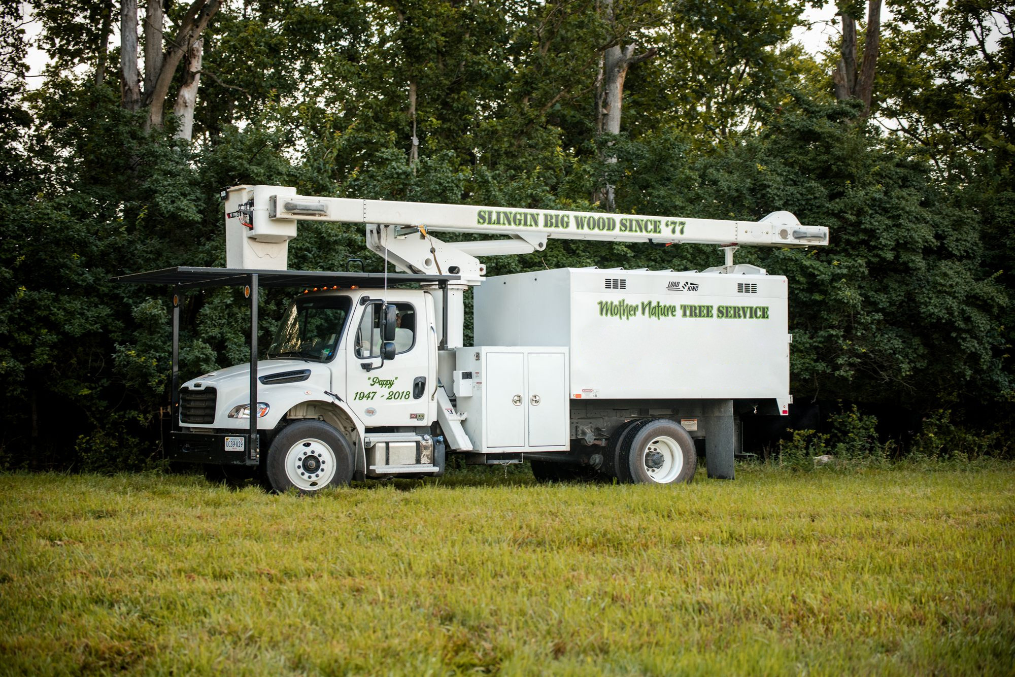 Side profile of a bucket truck parked in a pasture with the boom stowed along the body in Winchester, VA